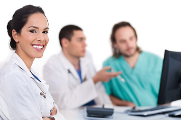 Image showing Smiling young doctor with other doctors behind her