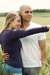 Image showing Young couple in meadow with the hands in the air, hugging