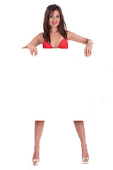 Image showing Young smiling woman in red bikini holding white blank board