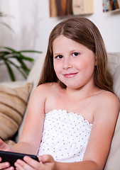 Image showing Young smiling girl looking at you in living room