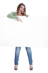 Image showing Happy beautiful woman pointing out the blank white board