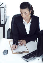 Image showing Busy business lady making her notes on the clipboard