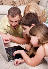 Image showing Domestic family of four lying and working with laptop