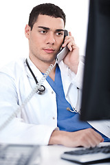 Image showing Portrait of male physician holding receiver and looking the computer