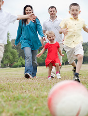 Image showing Sportive family playing football on the green lawn