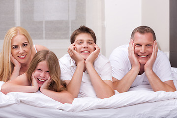 Image showing Beautiful family lying on bed smiling and looking at you