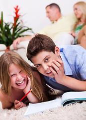 Image showing Two young kids lying with a book in living room