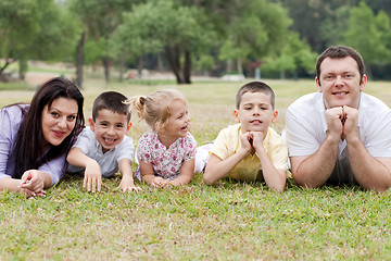 Image showing Cheerful family of five lying on lawn in the green park