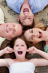 Image showing Happy family of four lying on the carpet with their heads together