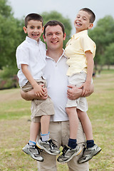 Image showing Close up shot of curious father carrying his sons in his both hands