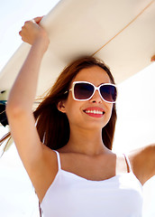 Image showing Smiling beach woman holding surfboard on her head