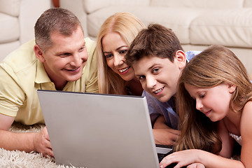 Image showing Family lying on carpet in living room with laptop