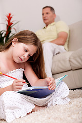 Image showing Cute girl studying with her father in the background