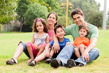 Image showing Family seated in park and smiling at camera