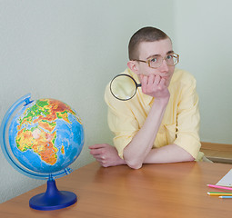 Image showing Young man with a magnifier and globe