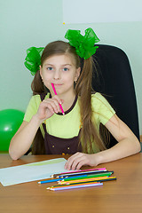 Image showing Girl sitting at a table with pencils