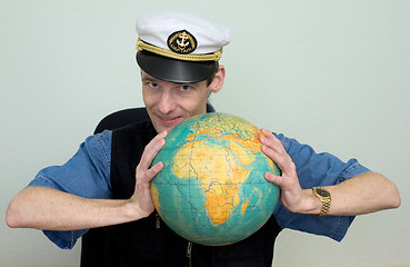 Image showing Man in a sea cap compresses globe in hands