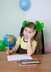 Image showing Girl sitting at a table with pencils