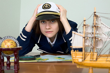 Image showing Scared girl in sea uniform at a table