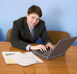 Image showing Businessman sits at table with the laptop