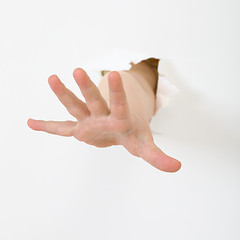 Image showing Child's hand stick out from hole