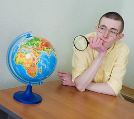 Image showing Young man with a magnifier and globe