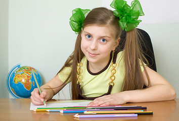 Image showing Girl sitting at a table with pencils