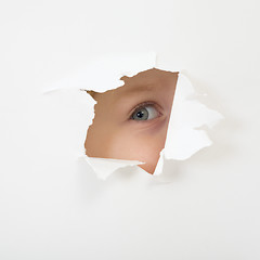 Image showing Eye looking through hole in sheet of paper