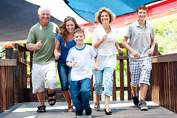 Image showing Family of five running on the wooden bridge