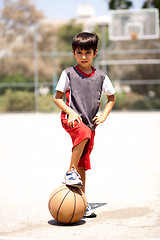 Image showing Smart kid holding basketball under his leg