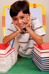 Image showing Cute young boy resting on books