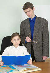 Image showing Tutor and schoolgirl with book and atlas