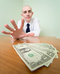 Image showing Man reaches for a batch of money