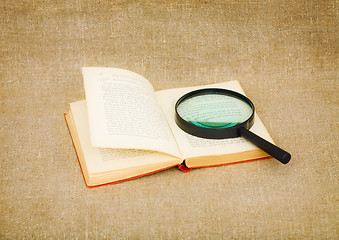 Image showing Old book and magnifier glass on canvas