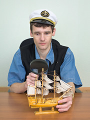 Image showing Man with a magnifier and model of a sailing vessel