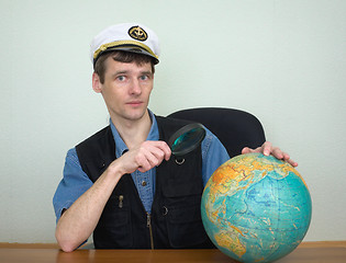 Image showing Guy in a sea uniform cap with globe and magnifier