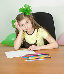 Image showing Girl sitting at a table with pencils
