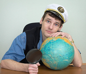 Image showing Man in a sea uniform cap with globe and magnifier