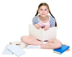 Image showing Girl sits among a heap of books