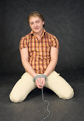 Image showing Man chained in a chain is kneeling