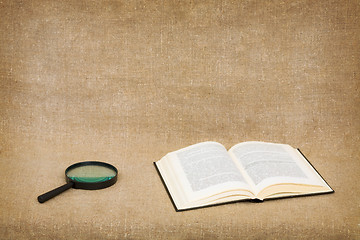 Image showing Open book and magnifier on canvas