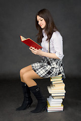 Image showing Girl reads the book, sitting on pile of books