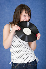 Image showing Girl biting a phonograph record on a blue