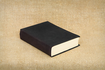 Image showing Old big black book on brown canvas background