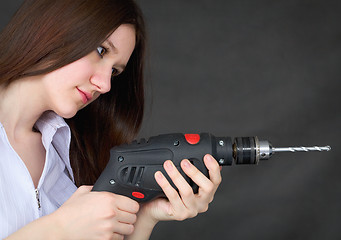 Image showing Young beautiful girl with drill in hands