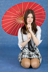 Image showing Girl with a red umbrella on blue background