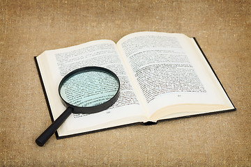 Image showing Open book and magnifier against a canvas - a still-life
