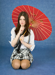 Image showing Young woman with umbrella on blue background