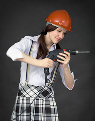 Image showing Girl in a helmet learns to use a drill