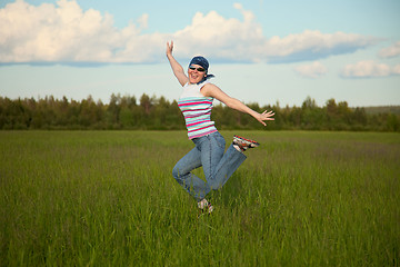Image showing Girl in bandana jumping on a green field